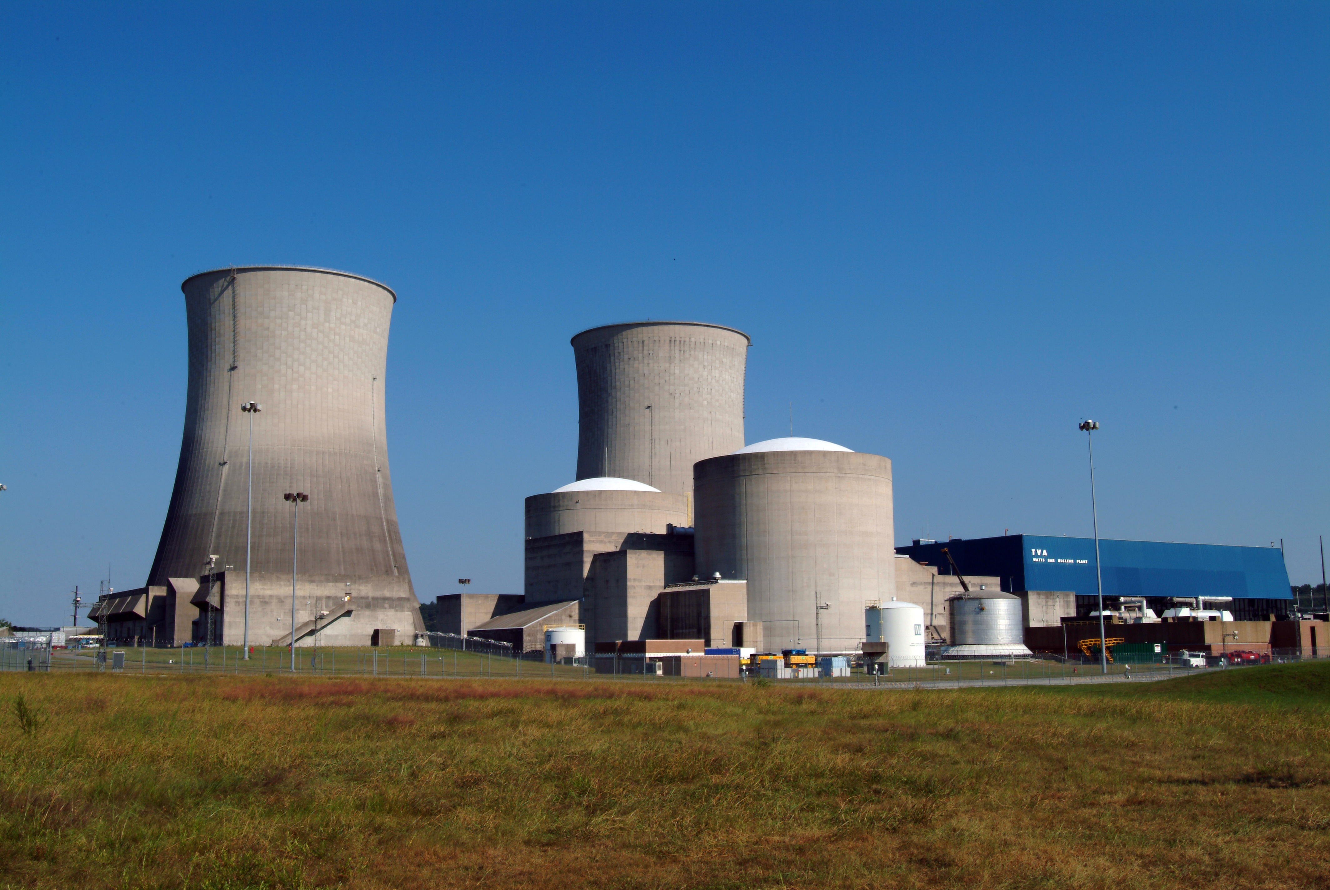 Elektrownia jądrowa Watts Bar z chłodniami kominowymi i kopułami reaktorów na tle błękitnego nieba.